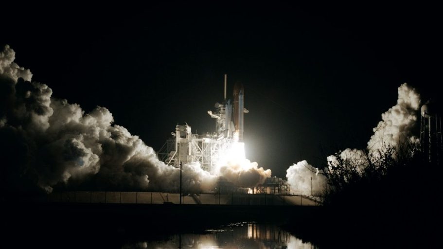 Rakete startet in der Nacht mit großem Feuer und Rauchwolken.